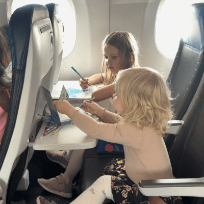 To små piger på 2 åg 5 år sidder i flyet og tegner i tegnebøger